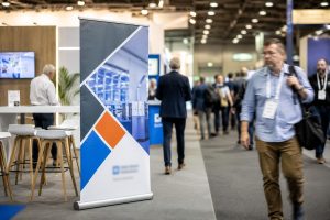 Professionele bedrukte roll-up banner naast een beursstand met voorbijlopende bezoekers
