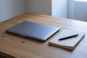 Gesloten laptop en notitieboek op een houten bureau