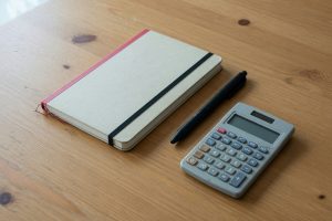 Gesloten notitieboek, pen en rekenmachine op een houten bureau