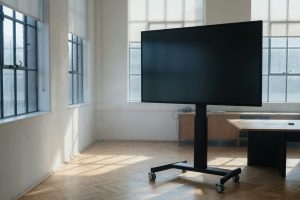 Groot scherm op een verrijdbaar statief in een lege zaal, ochtendlicht